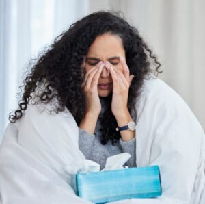 Person rubbing nose near tissue box