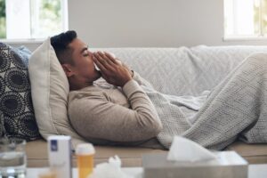 Young person blows nose while sick at home